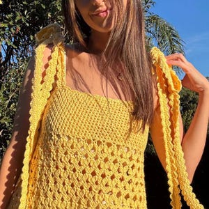 Peut inclure: Un haut en crochet jaune vif avec une encolure carr&eacute;e et des liens aux &eacute;paules. Le haut pr&eacute;sente un motif de point ajour&eacute;. Les bretelles sont longues et festonn&eacute;es. Le v&ecirc;tement est fait &agrave; la main, parfait pour l'&eacute;t&eacute;.