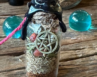 May include: A glass bottle with a black wax seal and a pentagram charm inside. The bottle is filled with dried herbs and crystals. The bottle is sitting on a wooden surface with a red string and a blue glass orb.