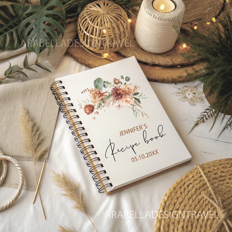 May include: A white spiral bound recipe book with a watercolor floral design in shades of brown, orange, and green. The text "Jennifer's Recipe Book 05.10.20XX" is printed on the cover.