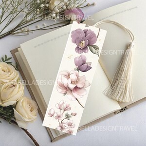 May include: A floral bookmark featuring watercolor illustrations of purple and pink magnolia blossoms and small flowers. The bookmark has a cream-colored background and a cream tassel. The text "ARABELLADESIGNTRAVEL" is printed on the bookmark.