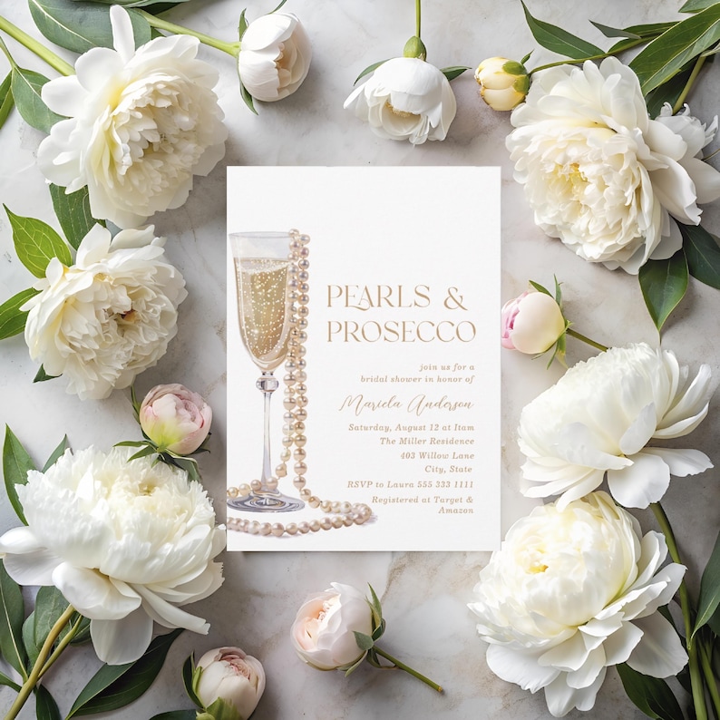 Puede incluir: Una tarjeta de invitaci&oacute;n blanca con letras doradas para una despedida de soltera. La invitaci&oacute;n dice "Pearls & Prosecco" e incluye el nombre de la novia, la fecha, la hora y el lugar. La tarjeta presenta una ilustraci&oacute;n de acuarela de una copa de champ&aacute;n con un collar de perlas.