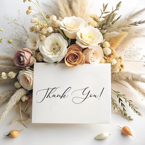 Puede incluir: Una tarjeta blanca con las palabras "&iexcl;Gracias!" escritas en cursiva negra. La tarjeta est&aacute; rodeada de un ramo de flores secas, incluyendo hierba de la pampa beige, rosas blancas y crema y flores de color melocot&oacute;n.