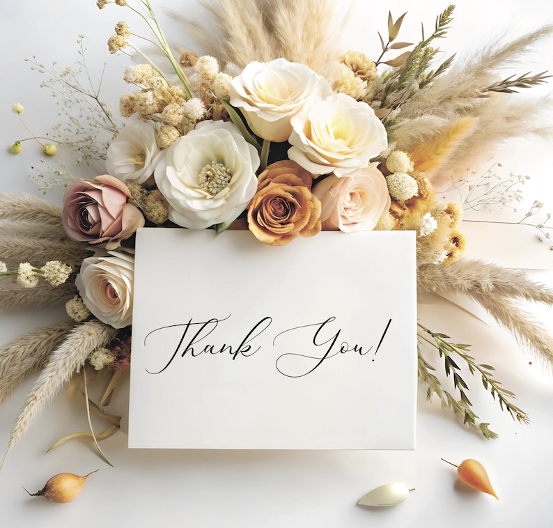Puede incluir: Una tarjeta blanca con las palabras "&iexcl;Gracias!" escritas en cursiva negra. La tarjeta est&aacute; rodeada de un ramo de flores secas, incluyendo hierba de la pampa beige, rosas blancas y crema y flores de color melocot&oacute;n.