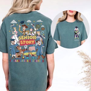 May include: Teal t-shirt with a colourful graphic of animated characters, the text "SENIOR STORY" and "TO GRADUATION AND BEYOND." A smaller image shows a character with a graduation cap and the word "NAME."