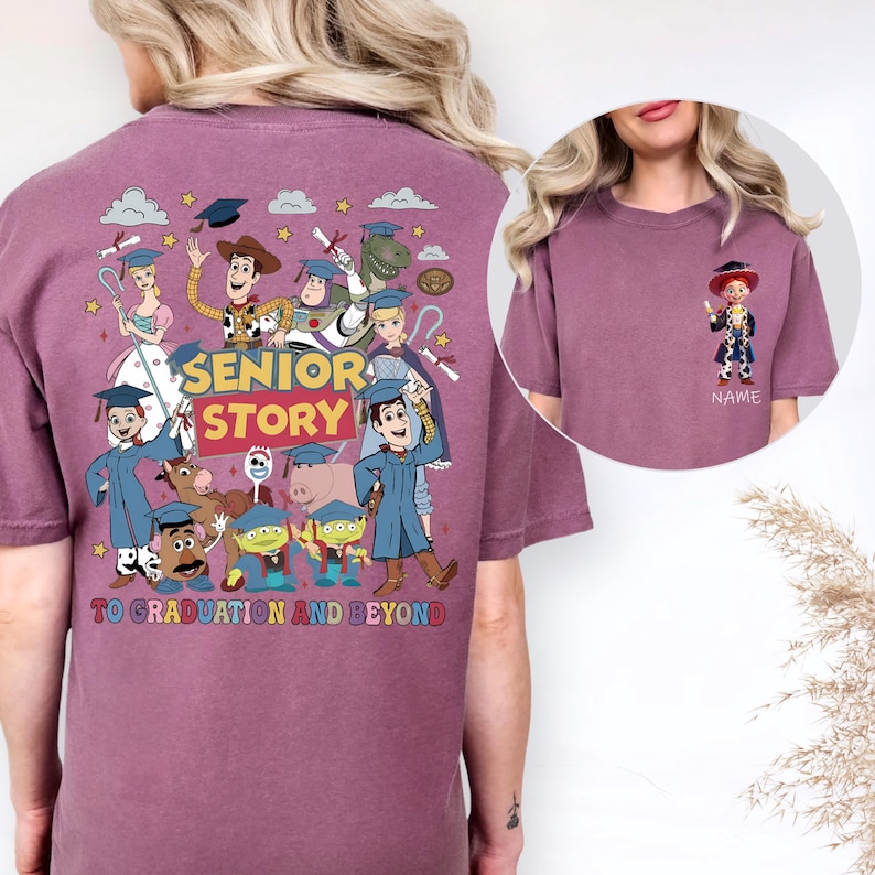 May include: A maroon t-shirt with a colourful graphic of Toy Story characters in graduation attire. The text "SENIOR STORY" and "TO GRADUATION AND BEYOND" are displayed. A smaller image of a character is on the front.