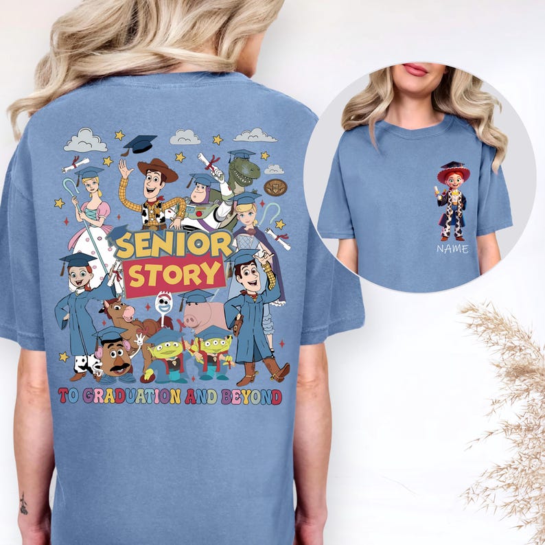 May include: A light blue t-shirt with a vibrant graphic of animated characters, including Woody and Buzz Lightyear, with the text "SENIOR STORY" and "TO GRADUATION AND BEYOND". A smaller character image is on the front. The design celebrates graduation.