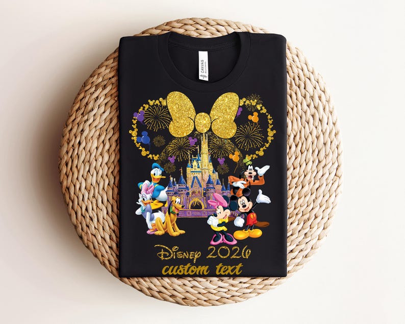 K&ouml;nnte beinhalten: Schwarzes T-Shirt mit einem Disney-Design mit Micky und Minnie Maus, Donald Duck und Goofy vor einem Schloss. Das Design beinhaltet eine goldene Schleife, Feuerwerk und den Text "Disney 2026 custom text."