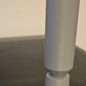 May include: A gray 3D printed joystick with a rounded top and a rectangular base.