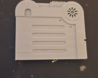 May include: A white plastic model of a vintage radio with a round speaker grill and a rectangular body with five horizontal lines.