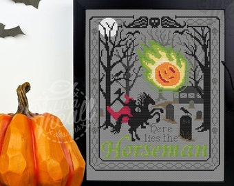 May include: A framed cross-stitch pattern featuring a headless horseman on a black horse with a red cape, a glowing orange and green fireball, a graveyard with tombstones, and bare trees against a gray background with the text Here lies the Horseman.