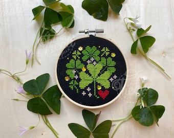 Peut inclure: Un cerceau de broderie noir avec un motif de trèfle à quatre feuilles vert et un cœur rouge. Le motif est entouré de paillettes dorées. Le cerceau est entouré de trèfles à quatre feuilles verts.