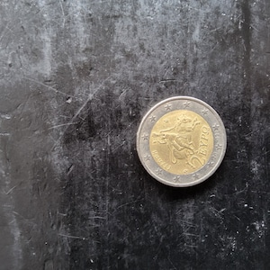 Puede incluir: Una moneda de dos euros de plata y oro con la imagen de un toro y el texto "2 EURO" en la moneda.
