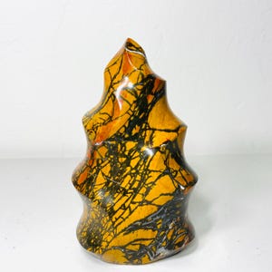 May include: A yellow, orange, and black patterned stone sculpture in the shape of a spire.
