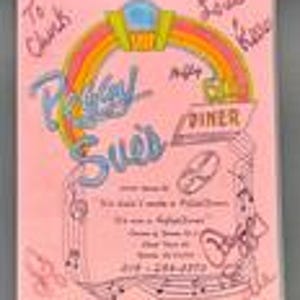 May include: A pink rectangular menu for Peggy Sue's Diner featuring a rainbow graphic, musical notes, and handwritten signatures. The text includes the diner name, address, and phone number 760-252-0706, with additional handwritten notes saying To Chuck and Love Kess.