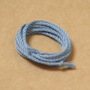 May include: A coil of light blue rope on a brown background.