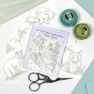 Peut inclure: Un ensemble de six patrons de broderie représentant des renards dans différentes poses. Les patrons sont imprimés sur des feuilles de plastique transparentes et sont livrés avec un paquet de fil à broder en vert et bleu. Le paquet comprend également une paire de ciseaux à broder.