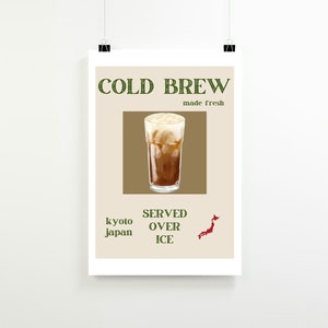 Pode incluir: Um cartaz com fundo castanho e texto verde que diz "COLD BREW made fresh". Um copo de café gelado com fundo castanho está no centro do cartaz. O texto "SERVED OVER ICE" está abaixo do copo de café gelado. O texto "kyoto japan" está à esquerda do copo de café gelado. Um contorno vermelho do Japão está à direita do copo de café gelado.