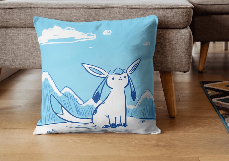 Puede incluir: Una almohada azul y blanca con una ilustraci&oacute;n de dibujos animados de un personaje Pokemon azul y blanco sobre un fondo azul con nubes blancas. El personaje Pokemon est&aacute; de pie sobre una cordillera azul y blanca.