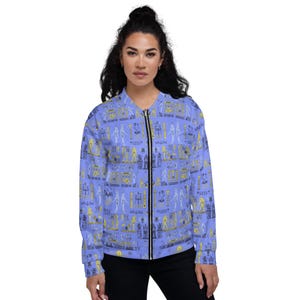 May include: A blue bomber jacket with a repeating pattern of yellow and black hieroglyphs. The jacket has a zipper closure and two pockets.
