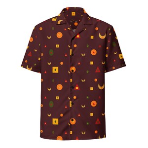 以下が含まれることがあります： 黄色、オレンジ、赤、緑の円、正方形、三日月が幾何学的に配置された、マロン色の半袖ボタンダウンシャツです。