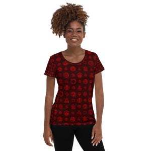 May include: A short-sleeved, scoop-neck t-shirt in a deep burgundy color. The shirt is covered in a repeating pattern of red circular designs. The overall style is casual and the shirt is made of a soft material.