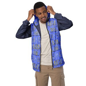 May include: A blue and navy blue hooded jacket with a zipper closure. The jacket has a pattern of hieroglyphics and figures in yellow and black on a blue background.