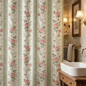May include: A floral shower curtain with a repeating pattern of pink roses and green leaves on a cream background. The curtain has vertical stripes with a light green border. The bathroom has a wooden vanity and a white sink.