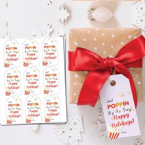 May include: Nine printable gift tags with a red and white striped background and a popcorn bucket with the text "Just Poppin' By To Say Happy Holidays!"