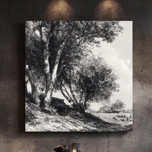 May include: A black and white landscape art print depicting trees on a hillside, mounted on a dark gray wall. The print hangs above a round wooden dining table with four black chairs. A decorative vase with tall, dried plants is on the right.