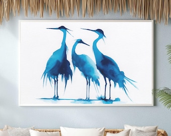 May include: A framed watercolor painting featuring three blue herons. The birds are depicted in shades of blue against a white background. The artwork is displayed above a wicker sofa and chairs in a room with a tropical theme.