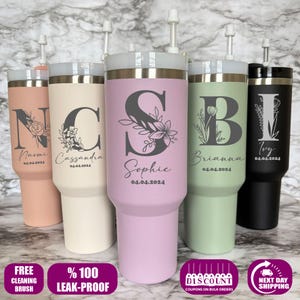 May include: Five personalized stainless steel tumblers with straws. Each tumbler features a different initial and floral design, with a name and date below. The tumblers are in various colors, including pink, beige, lavender, green, and black.
