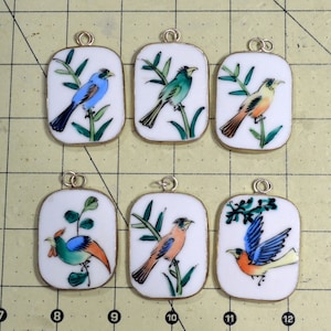 May include: Six porcelain pendants with silver accents, each featuring a different hand-painted bird on a branch. The birds are painted in vibrant colors, including blue, green, yellow, and orange.