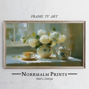 Può includere: Dipinto incorniciato di natura morta con un vaso di fiori bianchi, una tazza e un piattino e una teiera. Il dipinto ha una tavolozza di colori tenui e il testo "FRAME TV ART" e "Norrmalm Prints".