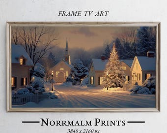 Puede incluir: Una impresión enmarcada de una escena de pueblo invernal. La obra representa casas cubiertas de nieve, una iglesia y un árbol de Navidad decorado, todo iluminado por una luz cálida. El texto "FRAME TV ART" y "Norrmalm Prints" son visibles.