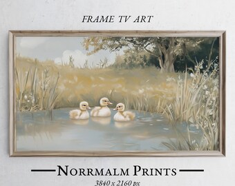 May include: A framed digital art print featuring three fluffy ducklings swimming in a pond. The artwork has a soft, muted color palette with a natural landscape background. Text at the top reads "FRAME TV ART" and at the bottom "Norrmalm Prints 3840 x 2160 px".