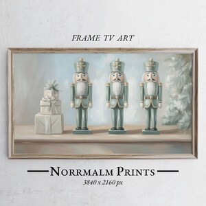 May include: Three blue and white nutcracker figurines stand in a row on a shelf. The nutcrackers are wearing traditional hats and have painted faces. The background is a light blue sky with white clouds. The image is framed in a light wood frame. "FRAME TV ART" is written at the top of the frame. "NORRMALM PRINTS" is written at the bottom of the frame. "3840 x 2160 px" is written below the text.