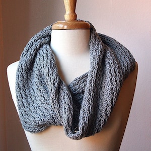 May include: A gray knitted infinity scarf on a white mannequin.  PDF Knitting Pattern.