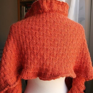 May include: A burnt orange knitted shawl with a high neck and ruffled edges.
