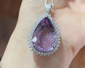 May include: A silver pendant necklace with a large pear-shaped amethyst gemstone surrounded by a halo of smaller clear gemstones.