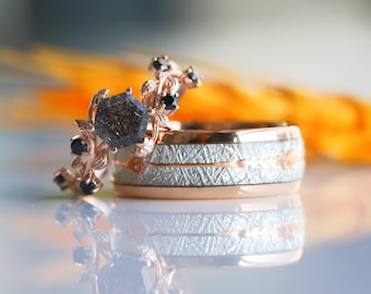 May include: A pair of wedding bands, one with a black diamond and black gemstones set in a rose gold band, and the other with a textured white gold band.