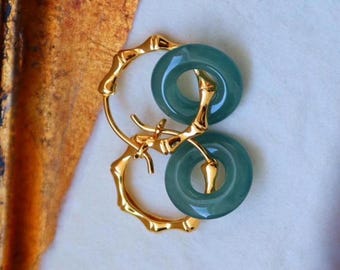 May include: Gold bamboo hoop earrings with a light blue jade stone accent. The jade stone is a double ring design.