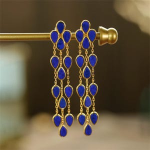 May include: Gold dangle earrings with multiple blue teardrop-shaped stones.
