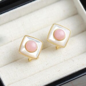 May include: A pair of gold tone clip-on earrings with a square shaped white mother of pearl base and a pink cabochon stone in the centre.