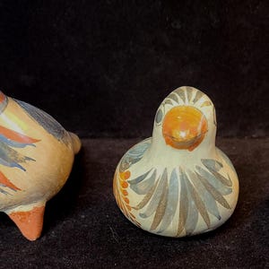 May include: Three ceramic bird figurines in varying sizes. The birds are painted with blue, orange, and tan colors. The largest bird stands on three legs. The other two birds are squatting. The birds have detailed feather designs.