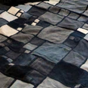 Może przedstawiać: Kołdra patchworkowa z geometrycznym wzorem w odcieniach szarości, czerni i bieli.