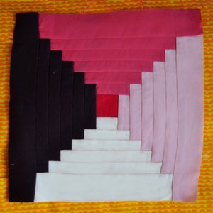 Może przedstawiać: Blok patchworkowy z wzorem chatki z bali w odcieniach różowego, białego, czerwonego i czarnego. Blok jest wykonany z pasków tkaniny zszytych ze sobą, tworząc kwadratowy kształt.