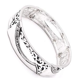 May include: Silver-toned hinged bracelet with a decorative design. The bracelet features a series of rectangular links, with intricate black cut-out patterns and small, clear gemstones. The bracelet is shown against a white background.