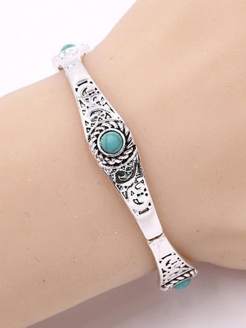 May include: Silver bracelet with an ornate design and turquoise stones.