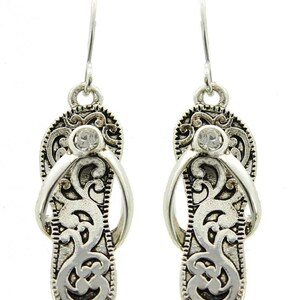 May include: Silver dangle earrings with a flip-flop design and a clear rhinestone in the center of each earring.