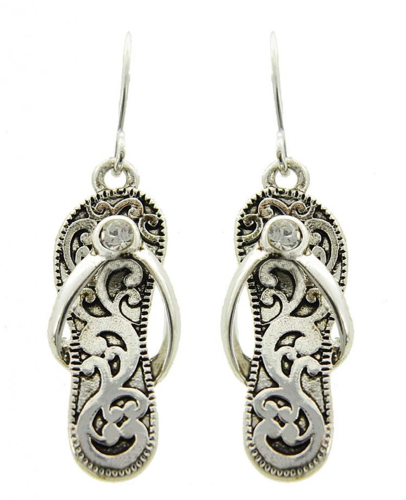 May include: Silver dangle earrings with a flip-flop design and a clear rhinestone in the center of each earring.
